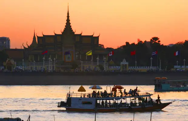 ourist boat on the Mekong River at sunset with the Phnom Penh Royal Palace in the background