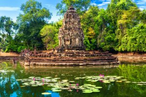 Ancient stone stupa of Neak Pean temple surrounded by a lake with water lilies in Angkor Siem Reap Cambodia