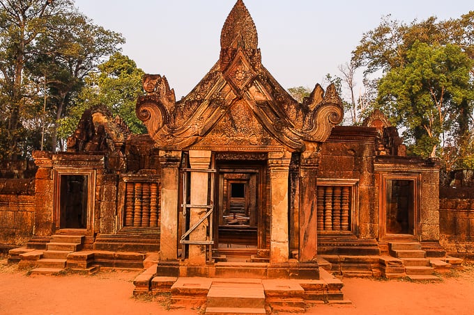 Intricate red sandstone carvings and devata lady statues at Banteay Srei temple in Siem Reap Cambodia
