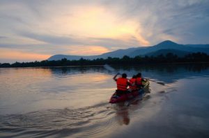 Tourists in life jackets kayaking on the Preak Tuek Chhu River in Kampot at sunset