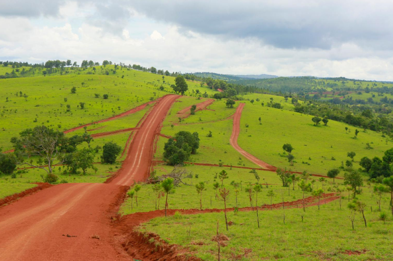 Scenic view of rolling green hills and a red dirt road in the Mondulkiri highlands of Cambodia