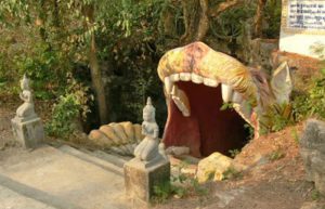 A colorful giant open-mouth monster statue serving as a cave entrance at Laang Phnom Touch in Banteay Meanchey Cambodia